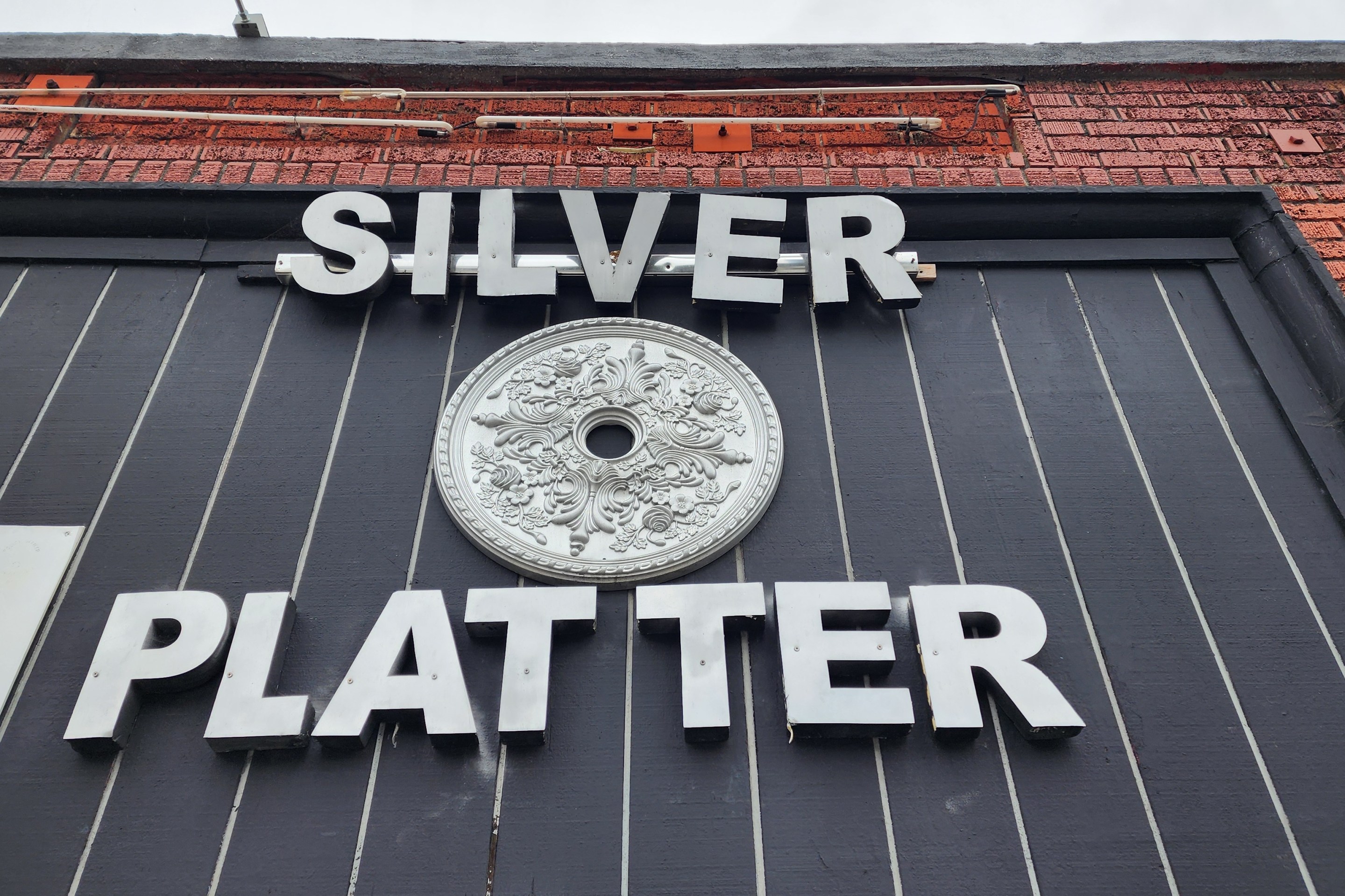 The words silver and platter with an emblem between them featured on the front of the Silver Platter on 7th Street.