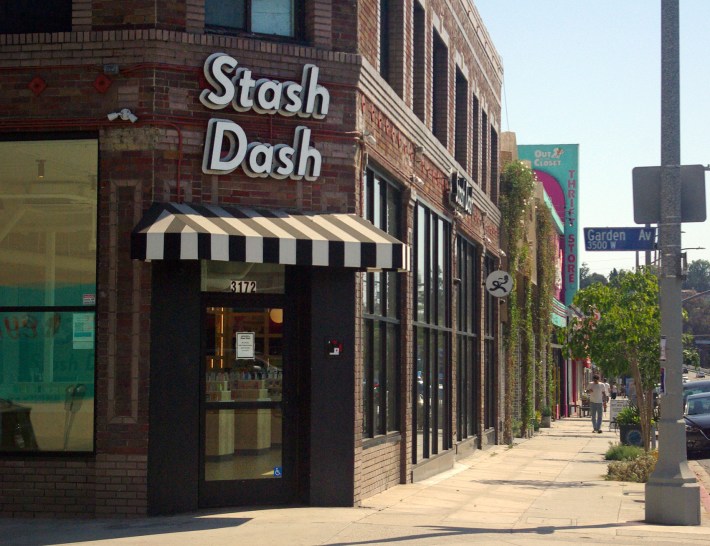 The "Stash Dash" signs hangs above a a black and white striped awning at their brick-wall store at Altwatter Village, Los Angeles on Tuesday, July 23, 2024. Stash Dash offers tools with advanced technology so consumers can make a more informed choice when purchasing cannabis products.