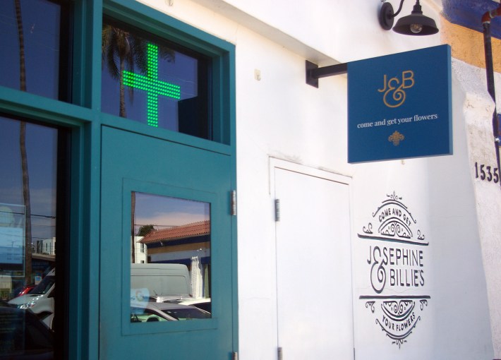 A neon green cross symbol is lit up above the door at Josephine and Billies In South L.A. on Tuesday, July 23, 2024. Josephine& Billie's not only wants to make waves as a Black and woman-owned cannabis dispensary, but also wants to make way for other women of color to thive in the cannabis industry. Photo by Caitlin Melgar for L.A. TACO.