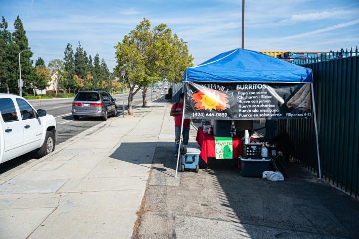 A blue tent over an LA burrito stand on the sidewalk