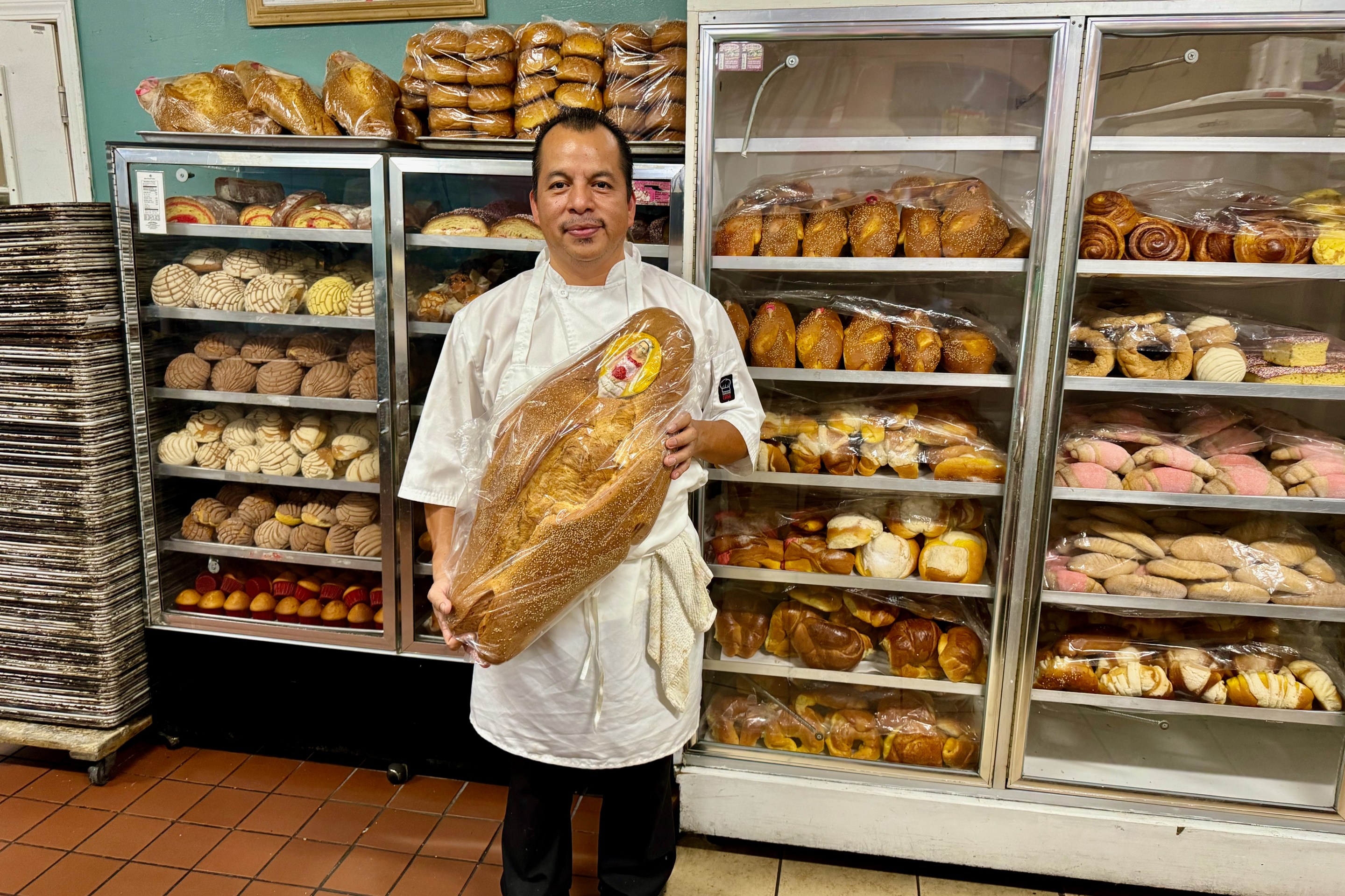 Sinecio Mecinas holding up his pan de muerto. Photo by Javier Cabral for L.A. TACO.