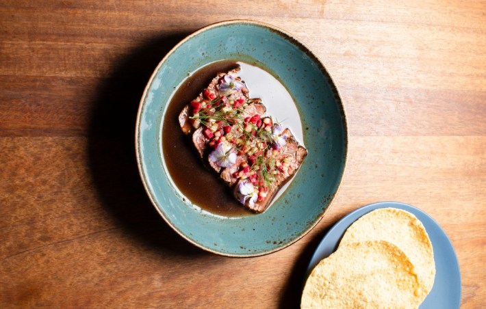 A blue plate with beef sirloin tiradito and a side of tortillas