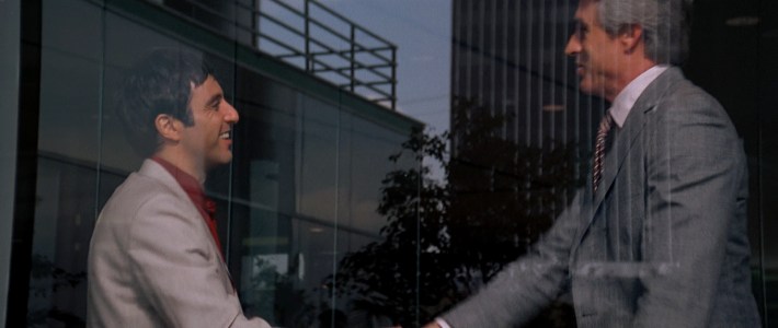 Tony shakes hands with his banker (Dennis Holahan). Screenshot via Universal Pictures.