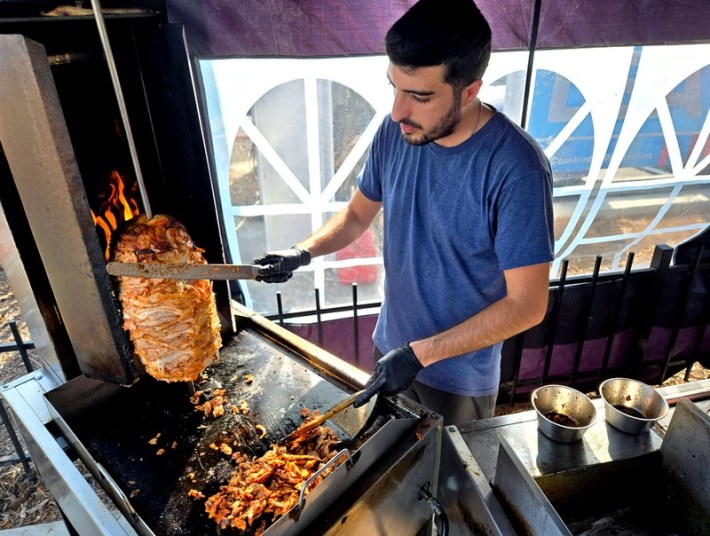 An employee of Lucky Chick slices chicken shawarma in Venice.