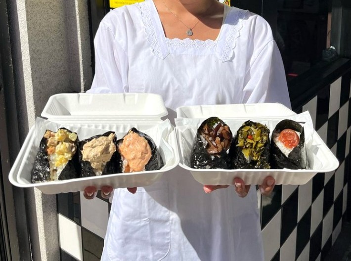 Two outstretched arms holding a selection of six different onigiri