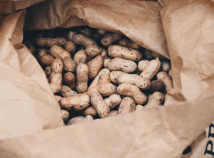 A bunch of peanuts peeking from a brown bag