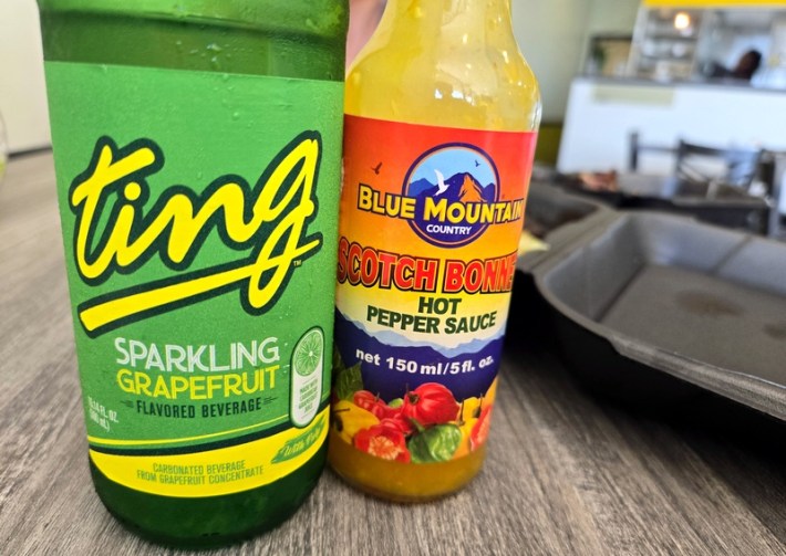 A bottle of Ting soda and a bottle of scotch bonnet pepper sauce on a table at Jerk Stop in L.A.