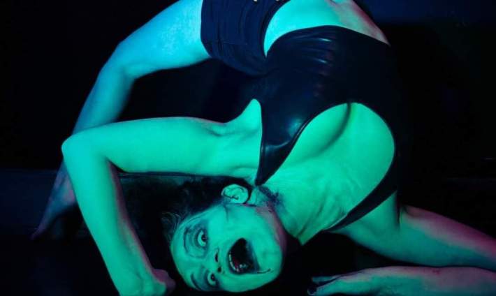 A contorting woman who looks possessed in a Halloween stage show